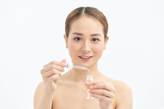 Closeup young Asian woman applying serum on her face isolated white background