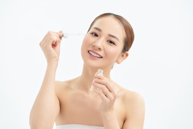 Closeup young Asian woman applying serum on her face isolated white background