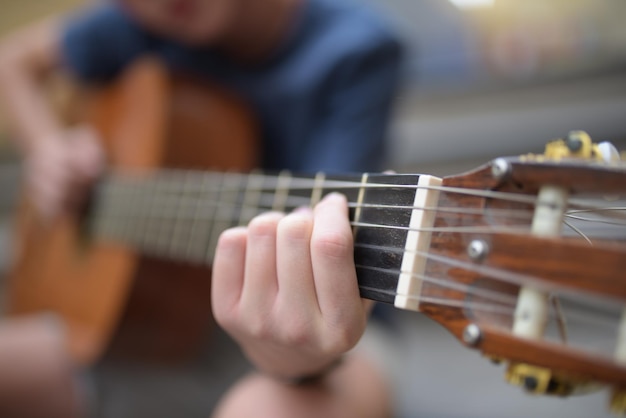 Closeup of a young kid playing guitar outdoors