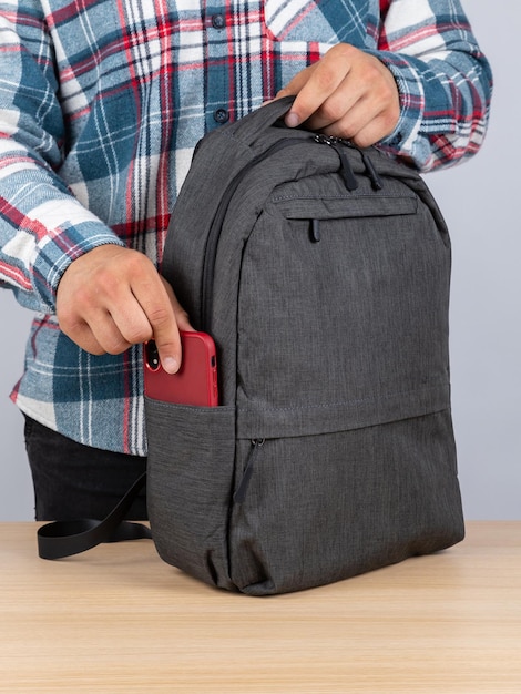 Closeup of a young male student taking out a phone from his backpack