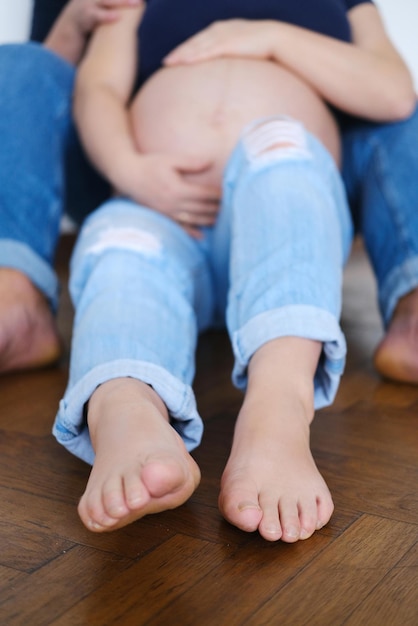 Closeup of young man touching pregnant wife's belly Focus on woman's legs