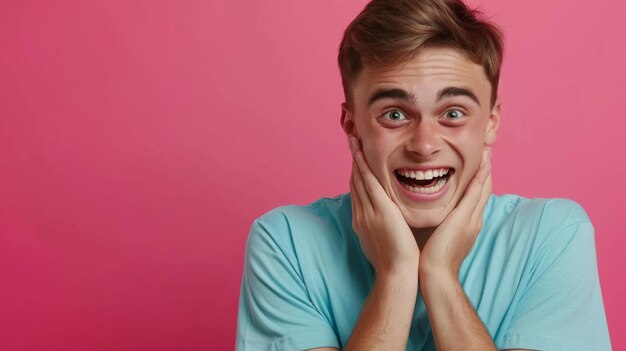 closeup of a young man with a joyful and surprised expression hands on his cheeks against a vibrant pink background