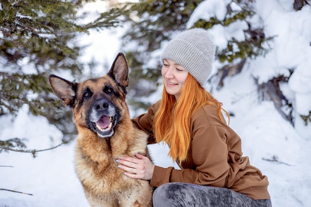 Closeup of a young pretty woman with red hair and a German shepherd outdoors Traveling with a pet a faithful companion