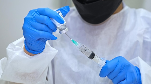 Closeup young woman doctor hands who use syringe draw vaccine from vial vaccine