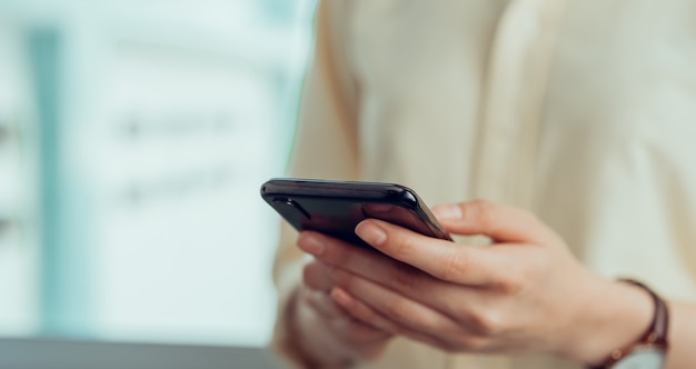 Closeup of young woman hand holding smartphone and chatting with friends at social network.