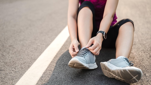 Closeup of young woman runner tying her shoelaces healthy and fitness concept