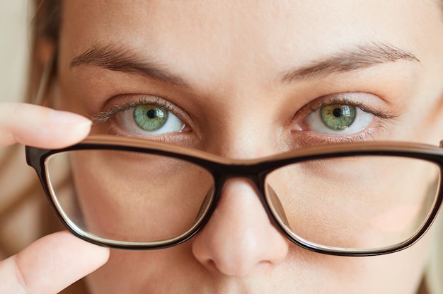 Closeup of a young woman taking off her glasses Vision correction concept spectacle frame