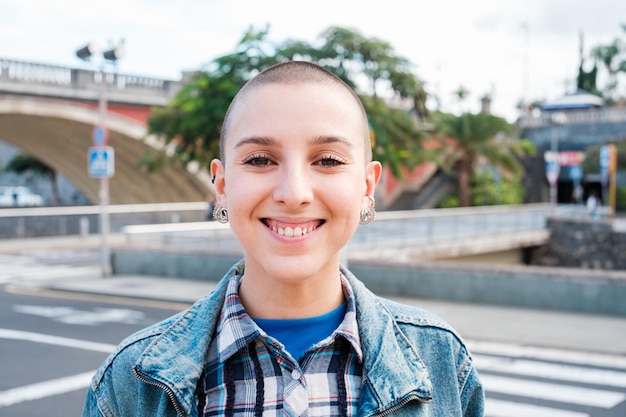 Closeup of young woman with shaved hair smiling in the city Concept Feminism lifestyle urban style