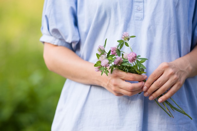 Closeup of young womans hands holding wild flowers Girl having fun and enjoying sun in the park Summer