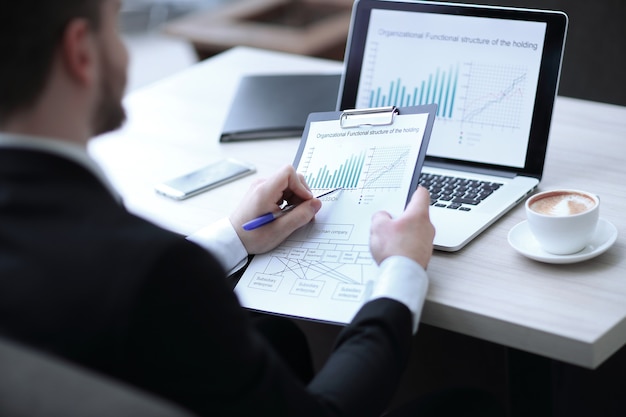 Closeupbusinessman checking financial documents sitting at the desk