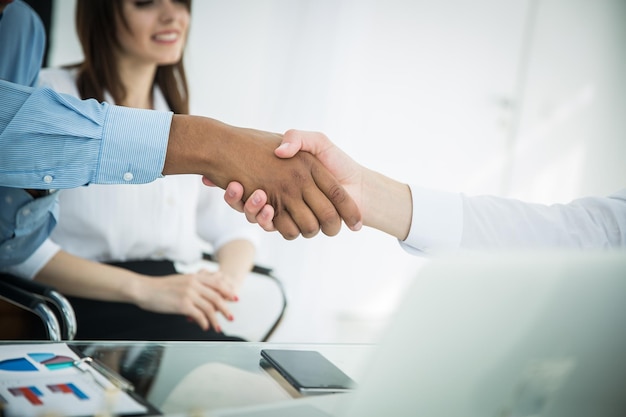 Closeupthe financial partners shaking hands over a Desk