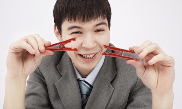 Closeupyoung businessman holding two clothespinssitting behind a Desk