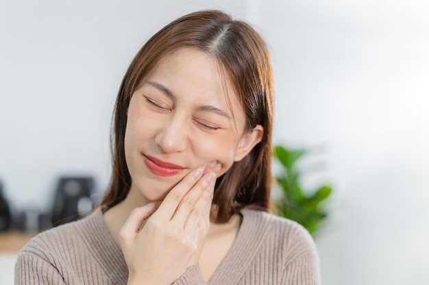 Closing eyes asian young woman touching cheek face expression from toothache tooth decay or sensitivity Having tooth or teeth problem or inflammation suffering from health Sensitive teeth people