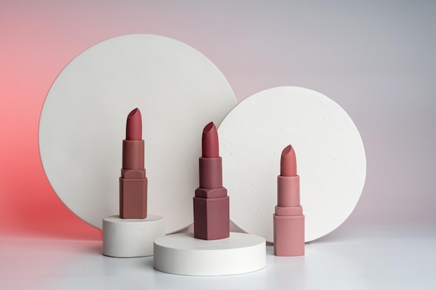 Closup of rose lipsticks standing near the white concrete podiums presenting product marketing merchandising