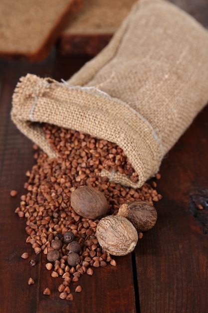 Cloth bag with buckwheat groats and spices on wooden