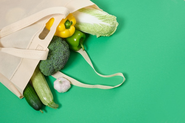 Photo cloth shopper with vegetables on a green surface eco friendly lifestyle concept