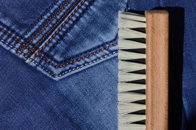 A clothes brush lies on folded jeans