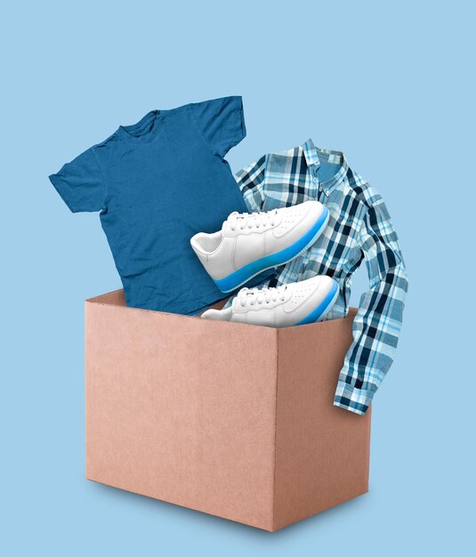 Clothes and shoes in cardboard box on blue background Minimal collage