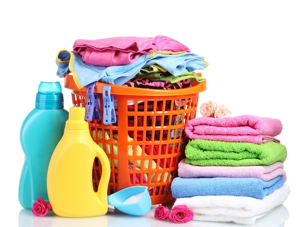 Clothes with detergent and washing powder in orange plastic basket isolated on white