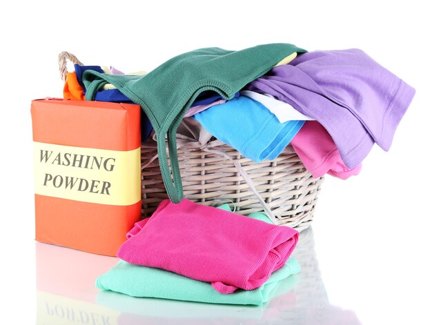 Clothes with washing powder in wooden basket isolated on white