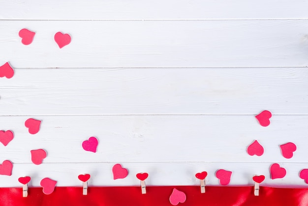 Clothespins with red hearts on a red ribbon on a white wooden background of Valentine Day