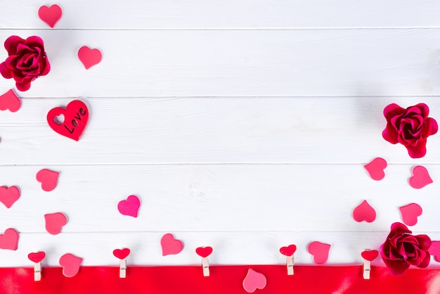 Clothespins with red hearts on a red ribbon on a white wooden background of Valentine Day