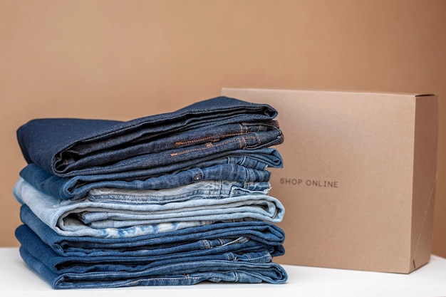 Clothing concept A stack of assorted jeans and a box for online delivery on the table