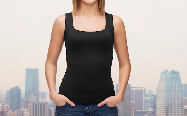 Photo clothing design, fashion, advertisement and people concept - close up of woman in blank black tank top over city background