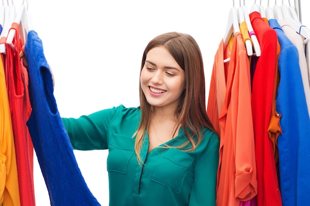 clothing, fashion, style and people concept - happy woman choosing clothes at home wardrobe