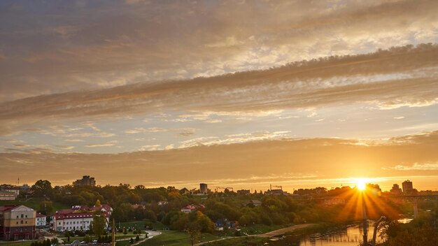 Clouds over the river and railway bridge during sunrise The rapid movement of clouds over the city and the factory with smoking chimneys Protection of the environment from harmful emissions