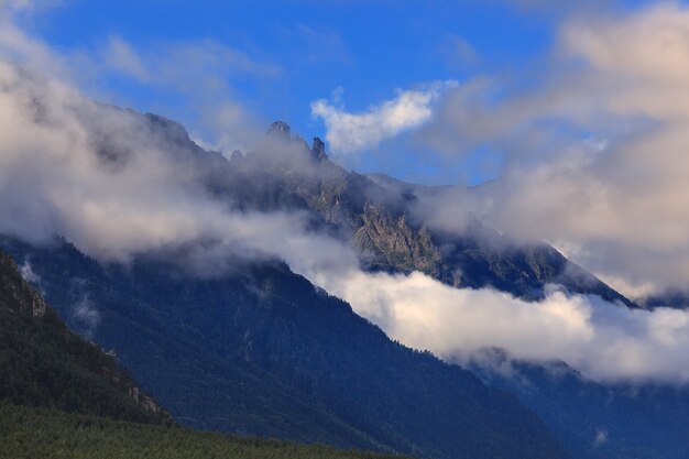 Clouds over the tops of rocky mountains overgrown with trees Photographed in the Caucasus Russia