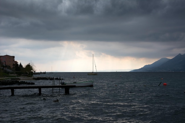 Under the cloudy dark sky the sea is cold A duck swims in the foreground And there are mountains