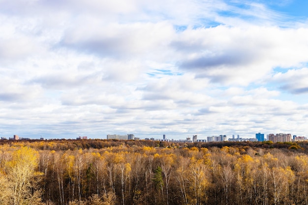 Cloudy sky over forest and city in autumn