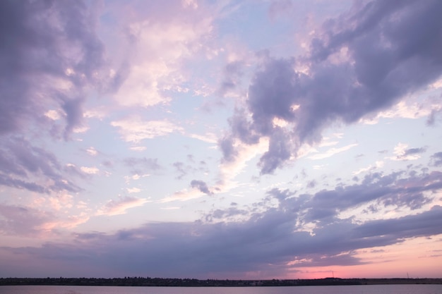 Cloudy sky with purple and pink clouds over the river at sunset