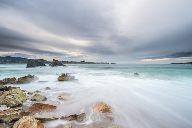 Cloudy sunset at Arnao beach with moderate waves