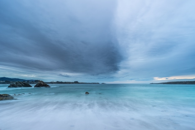 Cloudy sunset at Arnao beach with moderate waves