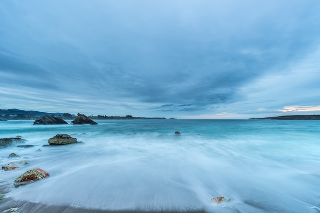 Cloudy sunset at Arnao beach with moderate waves