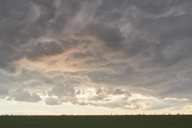 Cloudy sunset before thunderstorm in rural area summer in grass field with dramatic sky above