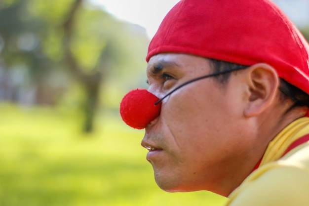 Clown close-up with nose and red cap.