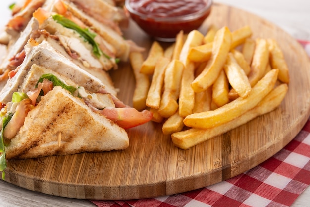 Club sandwich and French fries on wooden table