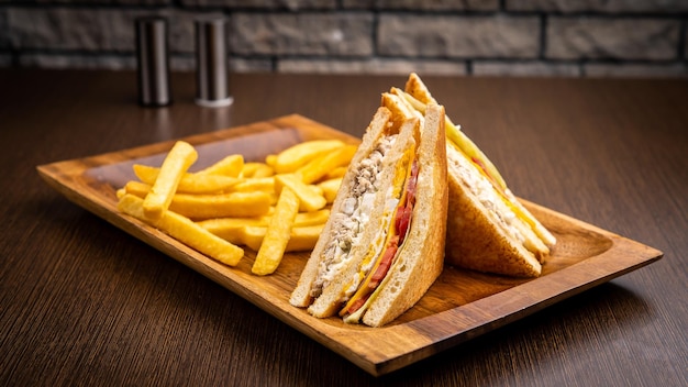 Club sandwich and fries isolated on wooden board side view on table fast food