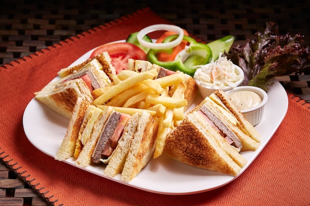 Club Sandwich with salad fries and mayo dip served in dish isolated on table side view of middle east food