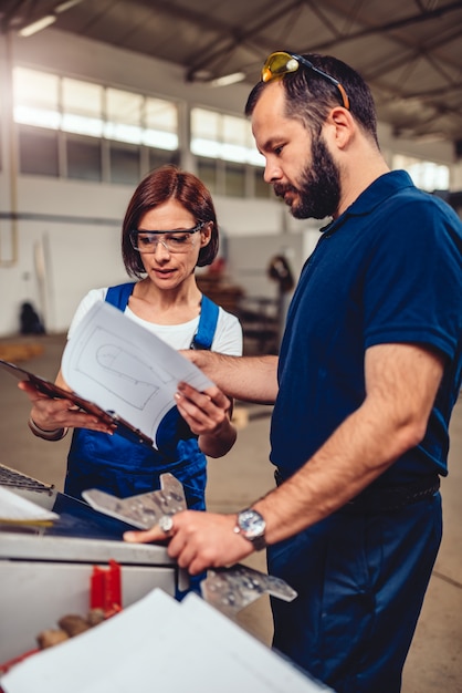 CNC Machine Operator and industrial engineer checking product drawing