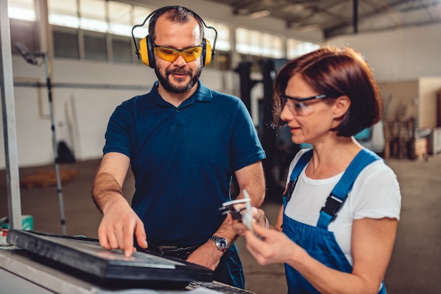 CNC Machine Operators working in industrial factory hall