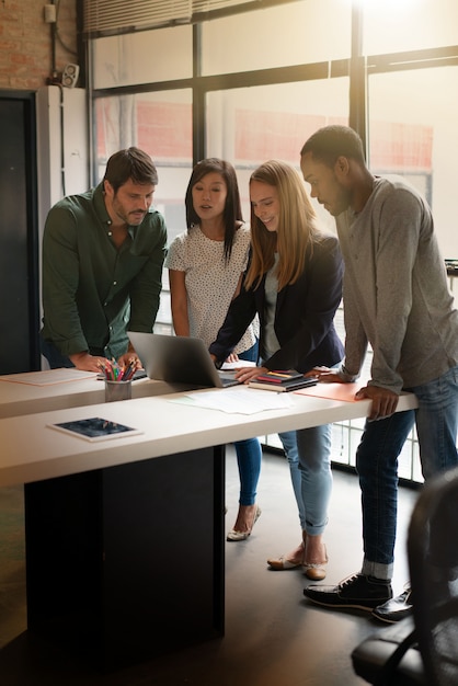 Co workers standing over desk going through presentation on computer