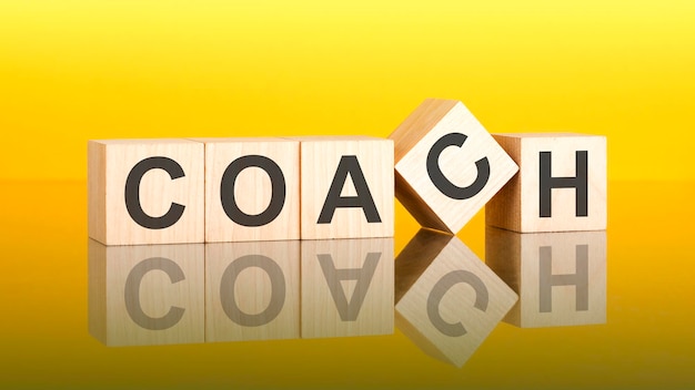 COACH text of on wooden cubes reflected from the bright yellow surface