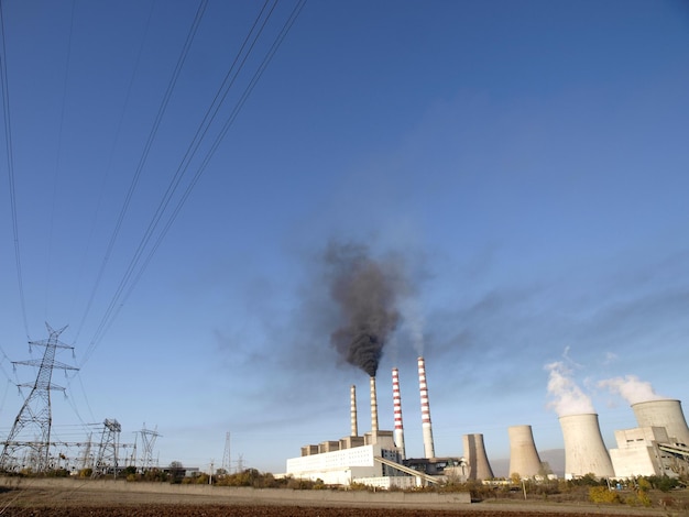 A coal fired power plant with smoke coming out of it.