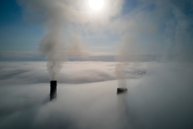 Coal power plant high pipes with black smoke moving upwards over clouds polluting atmosphere Production of electrical energy with fossil fuel concept