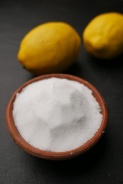 Coarse salt in a bowl and lemon on black background