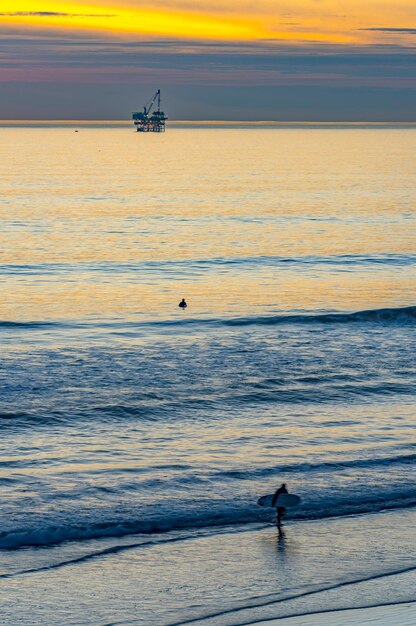 Coastal Convergence Oil Rig and Surfer at Huntington Beach California Harmoniously Uniting in 4k